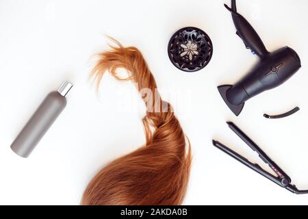 Set of tools dryer, iron and hair brush for hairstyle and red hair on white Stock Photo
