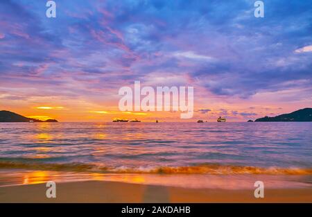 Walk the tideline of Patong beach on sunset and watch the scenic cloudscape, last sunlight and ships on the distance, Phuket, Thailand Stock Photo