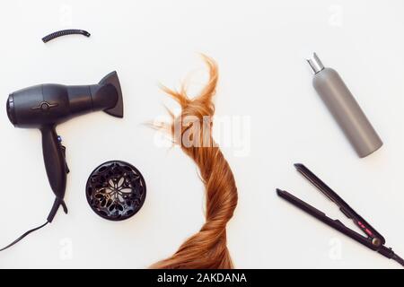 Set of tools dryer, iron and hair brush for hairstyle and red hair on white Stock Photo