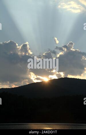 Sun rays emerging from behind a cloud before sunset Stock Photo