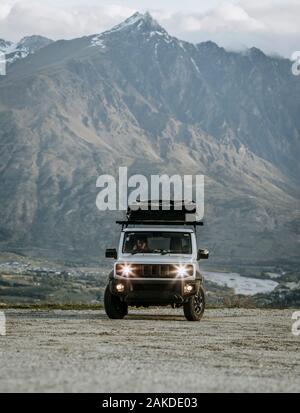 White SUV on dirt road in mountains near Queenstown, New Zealand Stock Photo