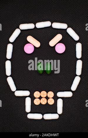 different colors and shapes of medical tablets lined in the form of a skull on a black background, concept, taking care of health, taking medications, Stock Photo