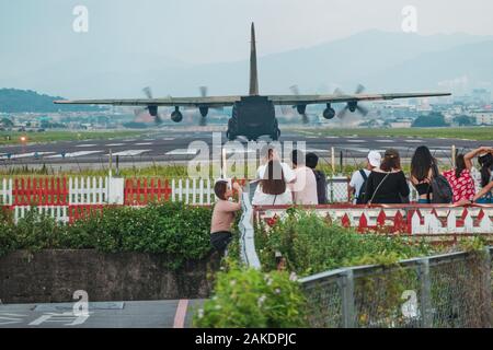 A crowd watches as a Republic of China Air Force Hercules C-130H cargo plane prepares for takeoff from Songshan Airport Stock Photo