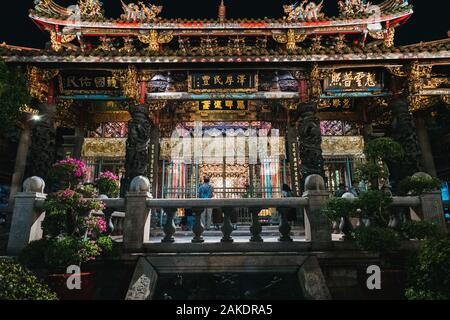 A worshipper inside Lungshan Temple at night, Taipei, Taiwan. Built in the 1700s for both Buddhist & Taoist philosophies Stock Photo