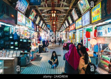 Muslim tourists pose for a photo in a quiet and empty Huaxi Street Night Market, at closing time, Taipei City, Taiwan Stock Photo