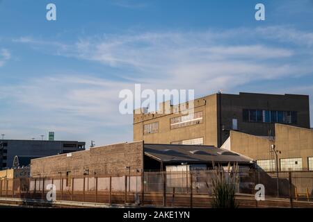 Grey industrial warehouse area behind fenced off railroad tracks Stock Photo