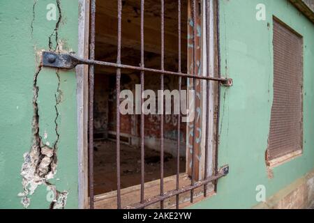 Steel gate of broken down building window with graffiti inside Stock Photo