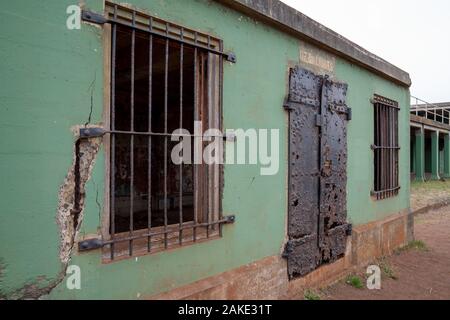 Green broken down building with rusted metal gates and doors Stock Photo