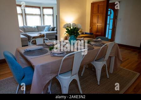 Simple table setting in a home dining room with couch in living room Stock Photo