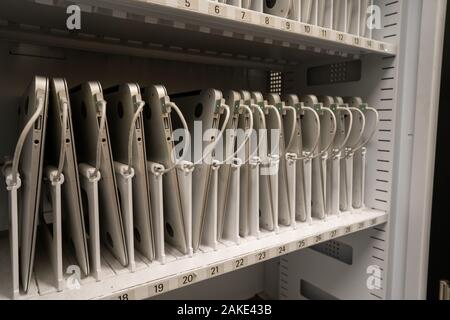 Macbook Air laptop computers being charged in storage for a classroom use Stock Photo