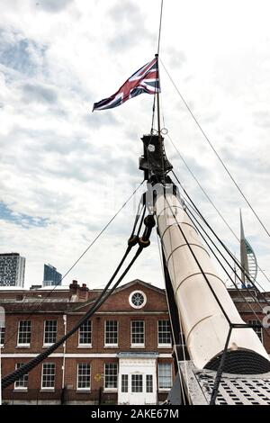 Bowsprit with British flag waving. HMS Victory. Large spar extending forward from vessel prow. Historic museum presentation in Portsmouth shipyard. Stock Photo