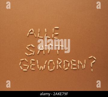 German question Did everyone get full? written with rice corn on a brown paper background, world food or nutrition concept Stock Photo