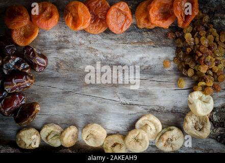 Assorted dried apricots, figs, dates and raisins on aged wood with copy space. Top view. Stock Photo