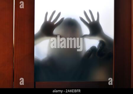 Horror woman behind the matte glass in black and white. Blurry hand and body figure abstraction. Stock Photo