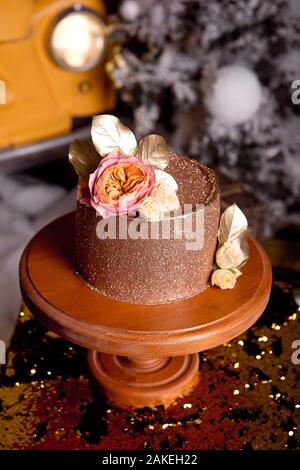Chocolate cake with raspberry filling and pistachio cream, decorated with roses and golden jelly sparkles in the New Year's interior Stock Photo