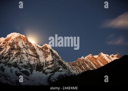 Night sky over Annapurna South and Annapurna Fang, with a glow from the moon setting behind the peak. Annapurna Sanctuary, Himalayas, Nepal, December 2012. Stock Photo