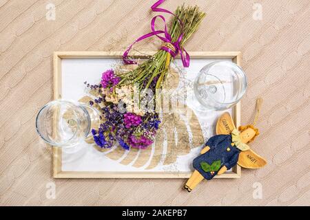 still life decoration from two empty wine glasses, a home-made rag angel toy and  bouquet of dried flowers. Stock Photo