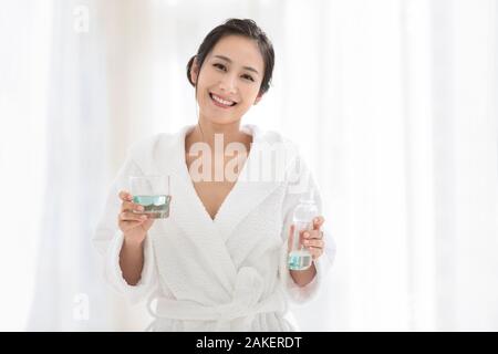Young Chinese woman using mouthwash Stock Photo