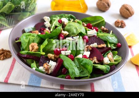 Salad with young spinach, boiled beets, blue cheese, nuts, cranberries in a bowl on a light background. Tasty diet fitness dish. Vitamin salad. Proper