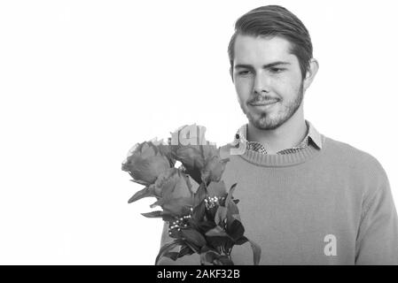 Young handsome Caucasian man holding red roses while thinking ready for Valentine's day Stock Photo