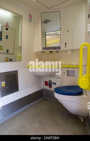 Railway toilet / lavatory with disabled access and bars, & basin sink seen through an open door on UK train near Southern London. UK (115) Stock Photo