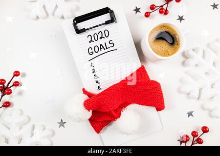 New year goals 2020 on desk. 2020 goals list with notebook, cup of coffee on white background. Goals, plan, resolutions, strategy, change, idea concep Stock Photo