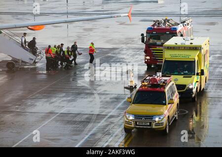 Emergency service responders, paramedics, ambulance paramedic attend an aeroplane / airplane / plane after a passenger has become sick / taken ill during an inbound flight to the airport. England UK (115) Stock Photo