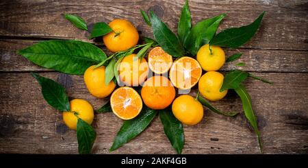 Tangerine, mandarines, clementine, citrus fruits with leaves on wooden table. Fresh tangerines citrus fruits background. Top view Stock Photo