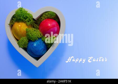 coloured Easter eggs in the wooden heart with real moss and Easter greetings Stock Photo