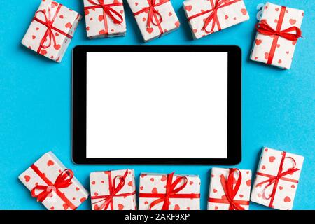 Top view of digital tablet surrounded with gift boxes on colorful background. Saint Valentine's day. Stock Photo