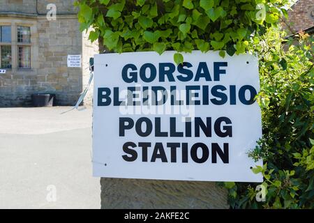 Polling station sign in Welsh and English language showing where people can go to cast their vote in an election in Wales UK Stock Photo