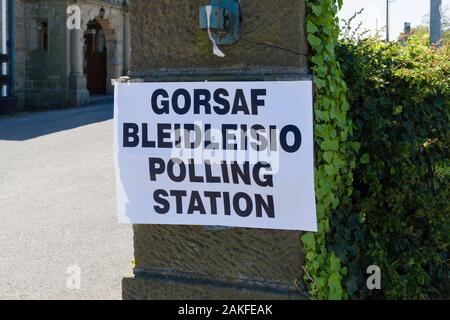Polling station sign in Welsh and English language showing where people can go to cast their vote in an election in Wales UK Stock Photo