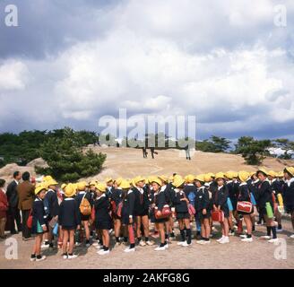 1960s, historical, group of Japanese school children on a school trip all dressed in blue uniforms and yellow sun hats. Stock Photo