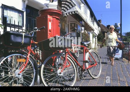 Royal Mail postal bikes leaning against a postbox, Sutton Valence, Kent, England, UK. Circa 1990's Stock Photo