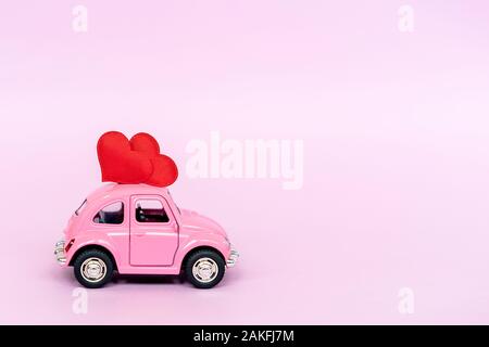 Red toy car delivering bouquet of pink rose flowers on pink background.  February 14 card, Valentine's day. Flower delivery. 8 March, International  Happy Women's Day. Stock Photo by ©KuzinaNatali 298951934