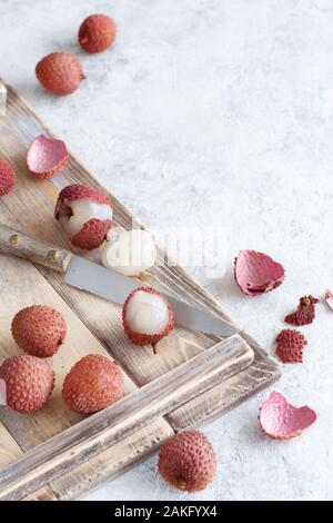 Fresh litchi fruits on a wooden tray on a white table close up Stock Photo