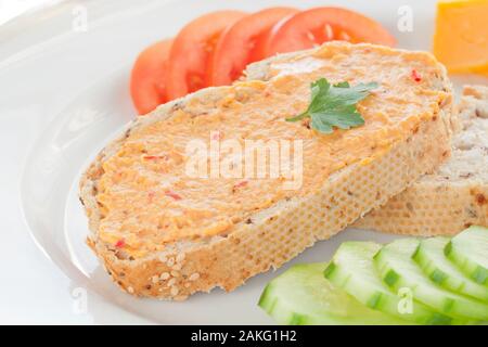 Close Up Image of Two Sesame Bread Slices with Hummus Spread, Tomato, Cucumber and Cheese on a White Plate Stock Photo