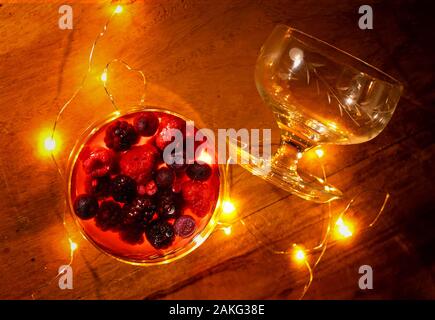 Two cocktail glasses with berries and lights glowing on wooden background still life Stock Photo