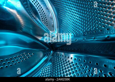 Futuristic look of a washing machine drum made of steel in blue light Stock Photo