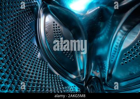 Futuristic look of a washing machine drum made of steel in blue light Stock Photo