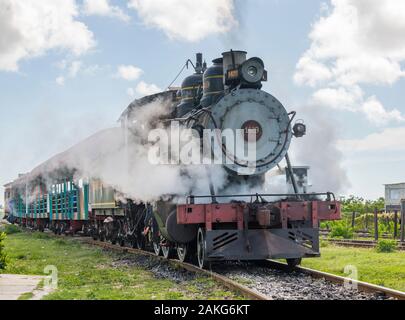 Old steam locomotive or railway train arriving to the platform of station Stock Photo