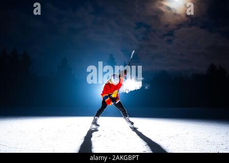 Hockey player on the ice by the full moon Stock Photo