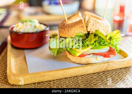 Delicious vegan bagel sandwich filled with sliced tomatoes, onion, avocado, vegan cheese, and various type of vegetables Stock Photo