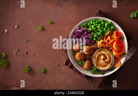 healthy vegan lunch bowl with falafel hummus carrot ribbons cabbage and peas Stock Photo