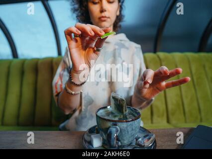 Woman brewing a fresh mug of tea with teabag in a cafe Stock Photo
