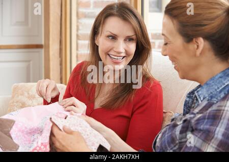 Two Mature Women Friends Making Quilt At Home Together Stock Photo