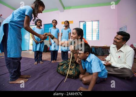 CAPTION: While Cluster Resource Person (CRP) Basavaraju observes, Sunithamma leads her primary school class in enacting a skit called 'Grandmother’s P Stock Photo