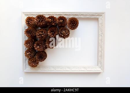 Pine cones inside vintage wooden frame isolated on white background from a high angle view Stock Photo