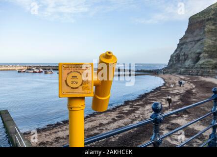 A Roland telescope on the esplanade overlooking the beach and harbour at Staithes, North Yorkshire, United Kingdom Stock Photo