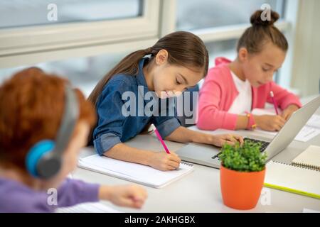Children working at the lesson using helpful devices Stock Photo